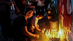 Varias personas colocan velas encendidas en el exterior de la guardería "Cantinho do Bom Pastor" tras un ataque mortal contra niños en Blumenau, Brasil, 5/4/2023