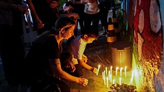 Varias personas colocan velas encendidas en el exterior de la guardería "Cantinho do Bom Pastor" tras un ataque mortal contra niños en Blumenau, Brasil, 5/4/2023