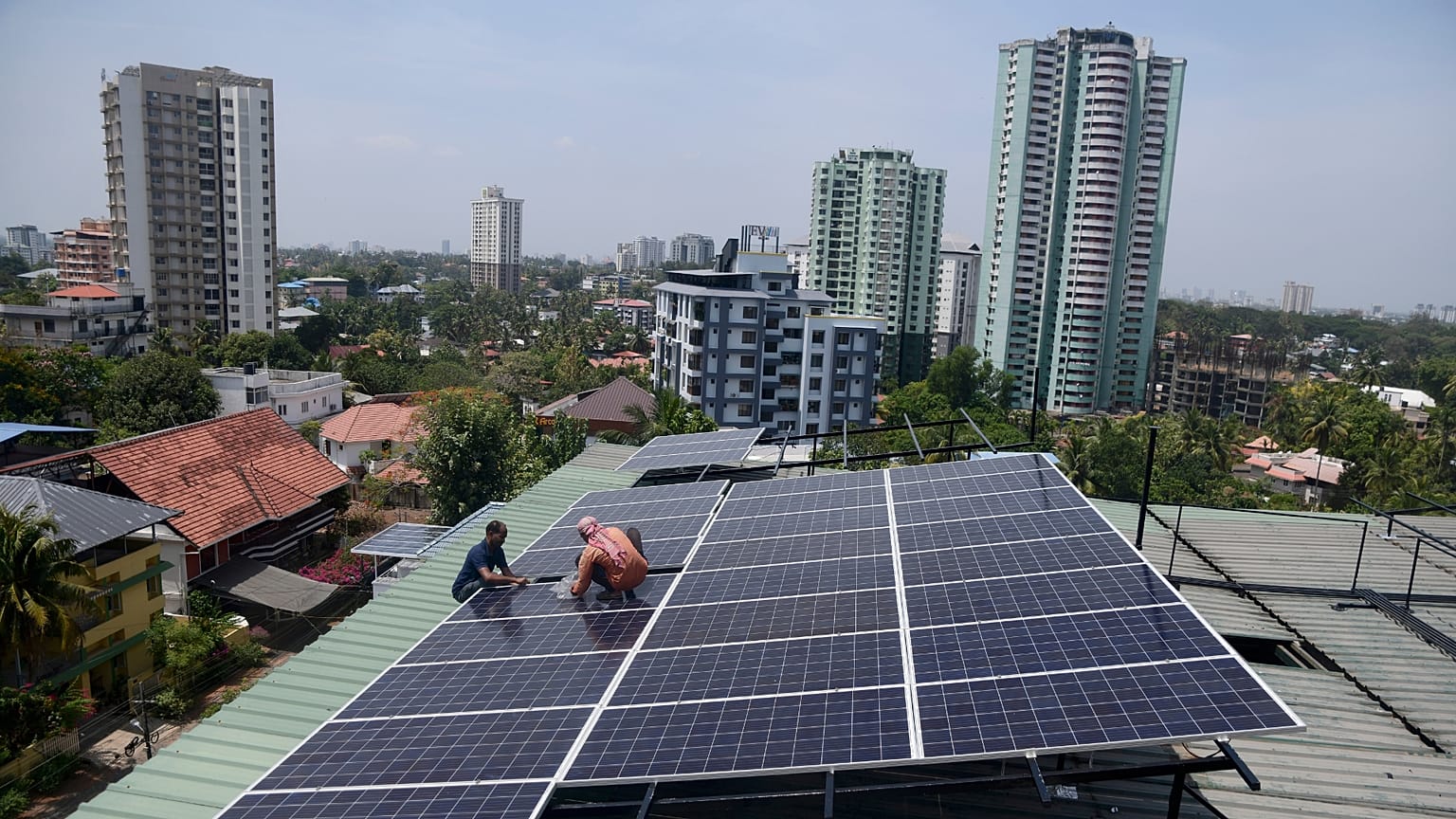 Workers install solar panels on the roof of a residential apartment in Kochi, southern Kerala state, India.