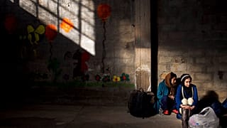 Two women wait to receive aid in Greece.
