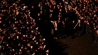 Faithful hold the cross as they take part in the Way of the Cross procession at the Colosseum on Good Friday, in Rome, Friday, April 7, 2023