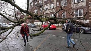 Gyalogosok törmelékek és a jégviharban letört faágak között lavíroznak Montrealban 2023. április 6-án.