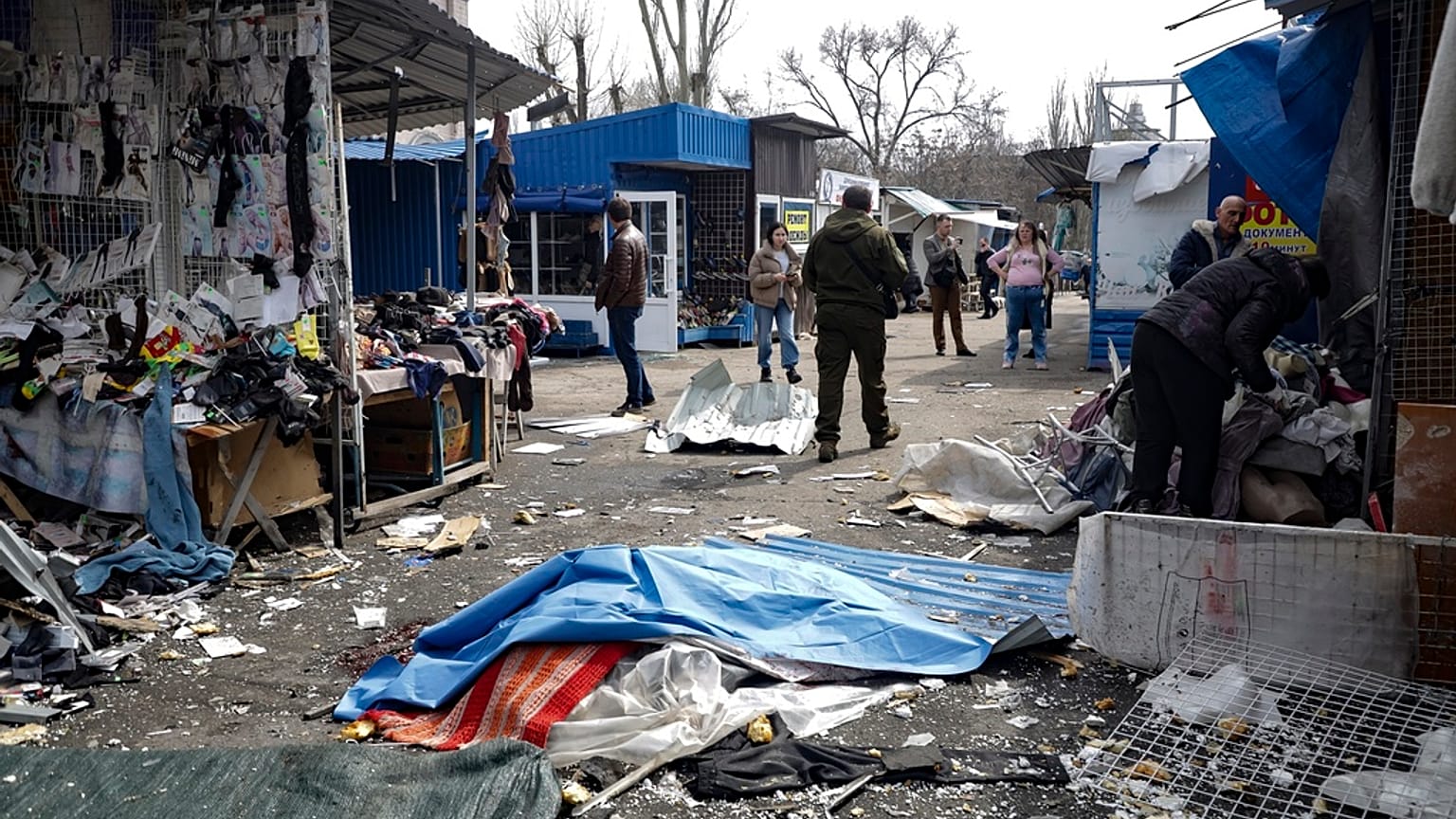 A lifeless body covered by plastic lies on the ground at a street market after the shelling that Russian officials in Donetsk said was conducted by Ukrainian forces.