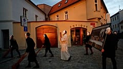 Participants dressed in black, wearing masks, beating drums and pushing small carts making a synchronized and loud sound take part in an Easter procession marching.