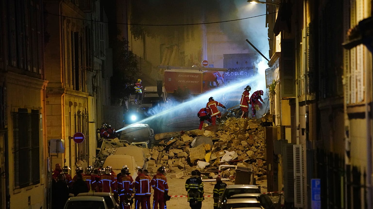 Firefighters gather near the street where a building collapsed early Sunday, April 9, 2023 in Marseille, southern France.