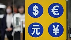 People walk near a sign of foreign currency outside a money exchange office at a shopping district in Seoul, South Korea, Tuesday, April 11, 2023. 