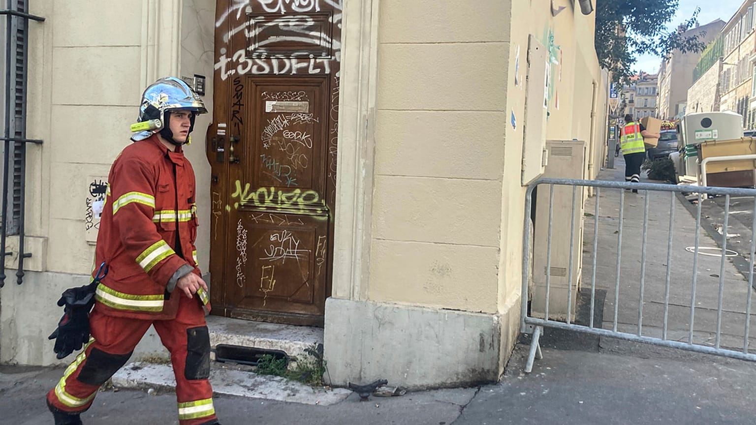 A firefighter walks near the scene where a building collapsed, in Marseille, southern France, April 10, 2023. 