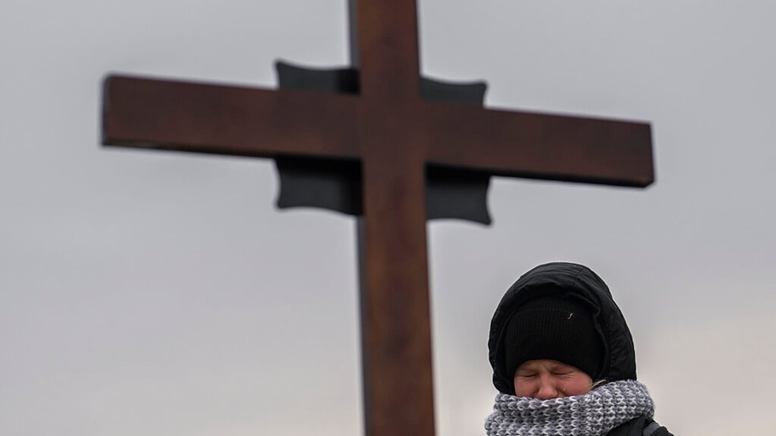 A Ukrainian girl cries above her father's grave, February 2023. 