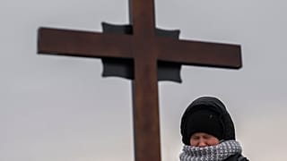 A Ukrainian girl cries above her father's grave, February 2023.