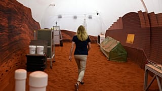 Dr. Suzanne Bell, Lead for NASA’s Behavioral Health and Performance Laboratory, walks through a simulated Mars exterior portion of the CHAPEA’s Mars Dune Alpha.
