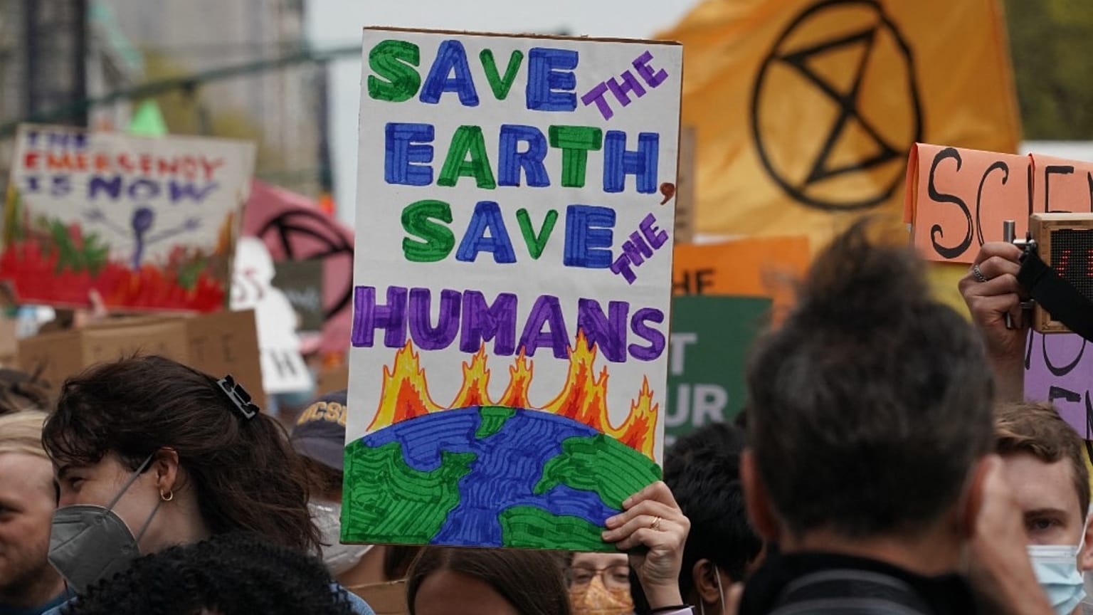 People carry signs at a march in New York one day after Earth Day 2022. 