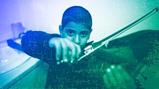 Jouan, a 10-year-old refugee from Aleppo, plays the violin as he practises backstage prior to a concert in Mytilene, Lesbos, December 2016