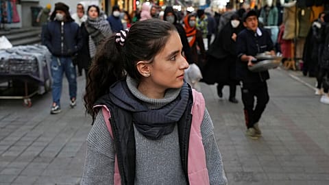 A woman walks around a commercial district without wearing her mandatory Islamic headscarf in downtown Tehran, Iran, Friday, Dec. 23, 2022.