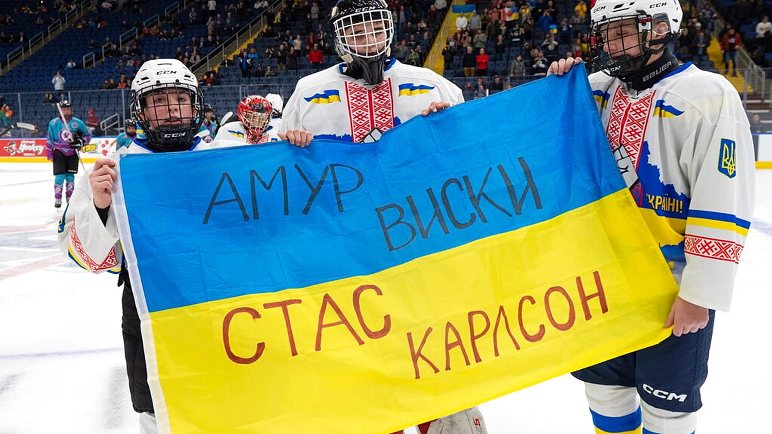 Ivan Bilozerov (balra), Matvii Kulish (középen) és Ihor Malovanyi ukrán jégkorongozók tartják az ukrán zászlót