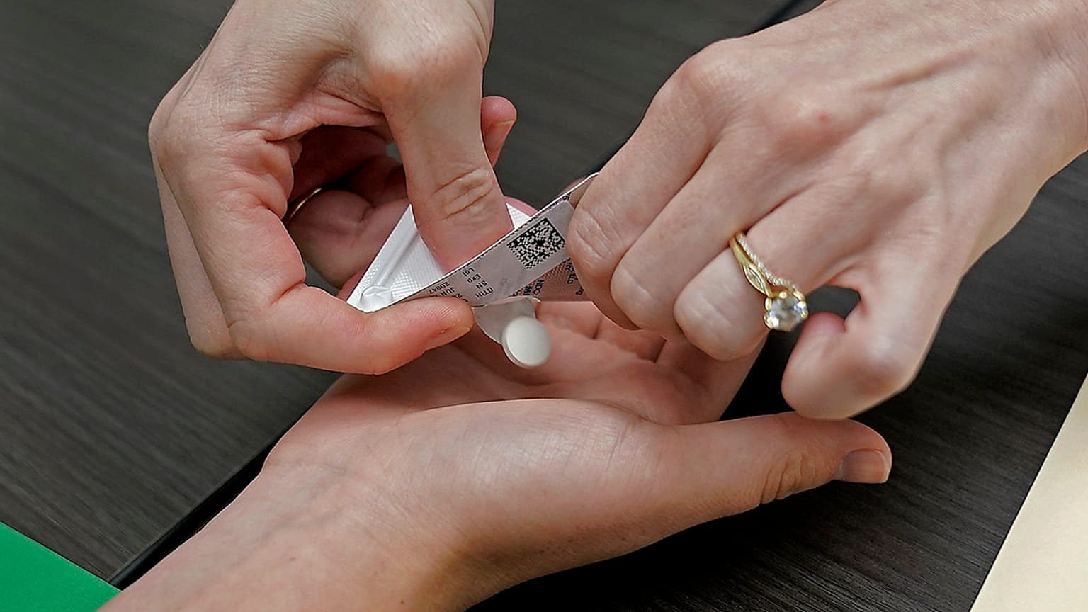 A patient prepares to take the first of two combination pills