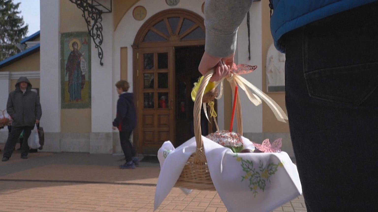 Close-up person holding easter basket filled with eggs, outside the church