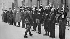 A Nazi SS-man inspects a group of Jewish workers in April 1943 in the Ghetto of Warsaw.