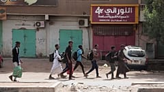 طلاب أمام متاجر مغلقة في الخرطوم في ثالث يوم من الاشتباكات