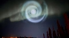 Eine helle, babyblaue Spirale, die einer Galaxie ähnelt, erscheint inmitten der Aurora für einige Minuten am Himmel über Alaska.