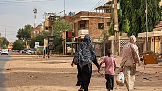 Duas mulheres e uma criança caminham por Cartum, Sudão, no dia em que foi decretado um cessar-fogo no país