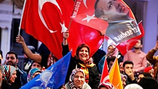 FILE - In this March 6, 2017 file photo women wave a Turkish flag and a flag showing President Erdogan, near Frankfurt