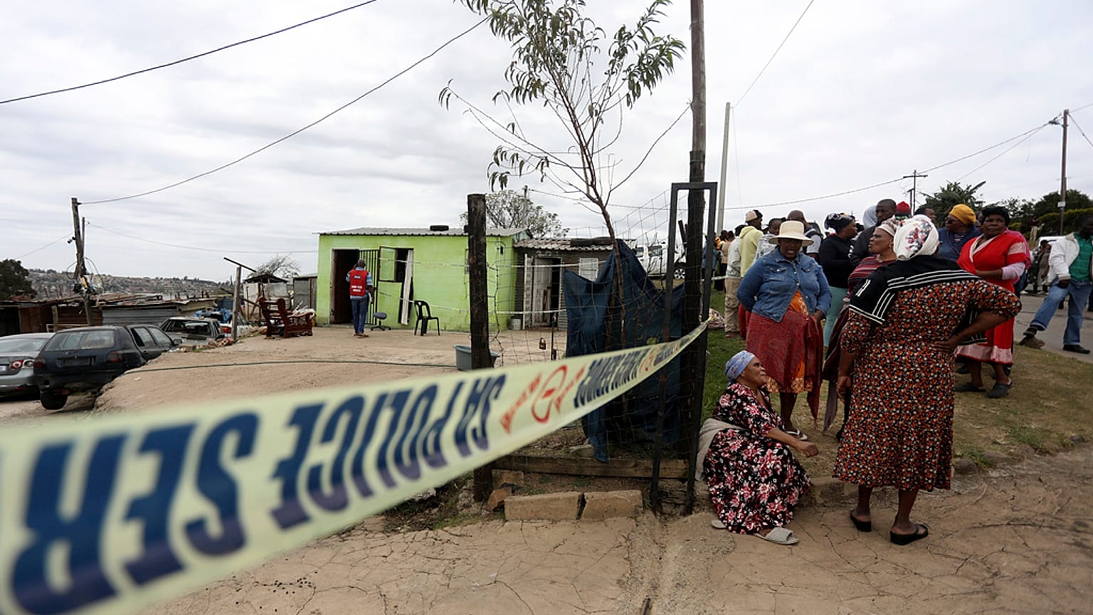 Women gather behind a police cordon where ten people from the same family were shot dead, Pietermaritzburg in the eastern KwaZulu-Natal province. Friday, April 21, 2023.
