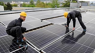 Workers install solar panels on an office building in Skopje, North Macedonia 19 April 2023.
