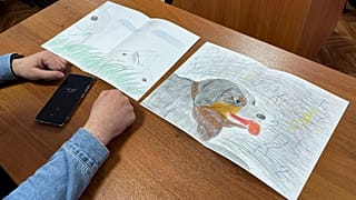 Moskalev's lawyer Vladimir Biliyenko shows drawings that Maria Moskaleva, daughter of Alexei Moskalev, drew for her father in a courtroom