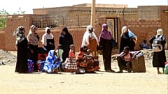 أشخاص يفرون من معارك الشوارع، ينتظرون مع أمتعتهم على طول طريق في الجزء الجنوبي من الخرطوم، في 21 أبريل/نيسان 2023.