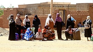 أشخاص يفرون من معارك الشوارع، ينتظرون مع أمتعتهم على طول طريق في الجزء الجنوبي من الخرطوم، في 21 أبريل/نيسان 2023.