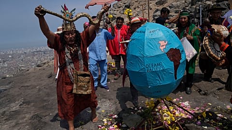 A shaman holds up a snake next to a geographic globe during a ritual calling for the earth's protection from contamination, one day before Earth World Day