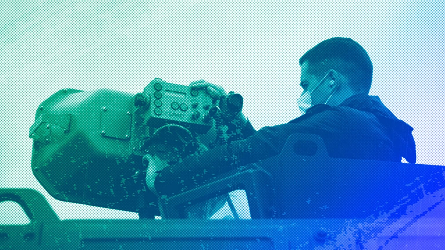 A Police officer operates a long range acoustic device, (LRAD), attached on a police vehicle, during a patrol alongside the Greek-Turkish border, May 2021