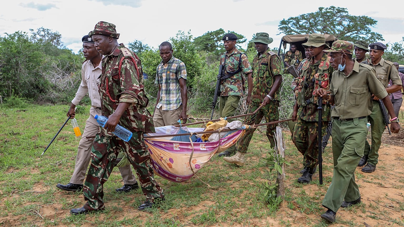 Police and local residents load the exhumed bodies of victims of a religious cult into the back of a truck in the village of Shakahola, near the coastal city of Malindi