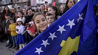 A Kosovo Albanian child holds the Kosovo flag during the military parade celebrations to mark the 15th anniversary of Kosovo's declaration of independence in Pristina in 2023.