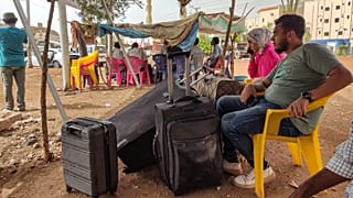 People wait with luggage before boarding a bus departing from Khartoum in the Sudanese capital's south.