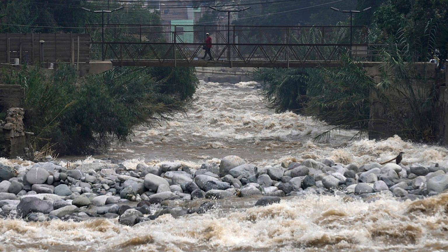 A woman walks on a bridge over the Rimac River, a day ahead of World Water Day.