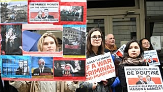 Demonstrators hold placards, including "why does Putin's ex-wife still have a house in Biarizza" near Svetlana Ivanova's apartment in Paris on Aprill, 23, 2023.