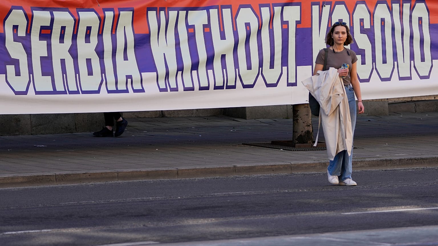 A woman passes by a billboard reading: ''Serbia without Kosovo would be like a human without heart'' at a protest in Belgrade. 24 March 2023