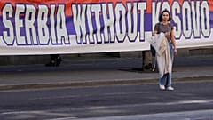 A woman passes by a billboard reading: ''Serbia without Kosovo would be like a human without heart'' at a protest in Belgrade. 24 March 2023
