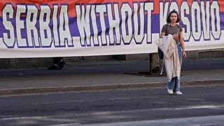 A woman passes by a billboard reading: ''Serbia without Kosovo would be like a human without heart'' at a protest in Belgrade. 24 March 2023