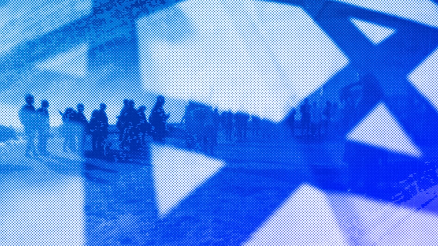 Israeli demonstrators are seen through the national flag during a protest against plans by PM Benjamin Netanyahu's government to overhaul the judicial system, March 2023