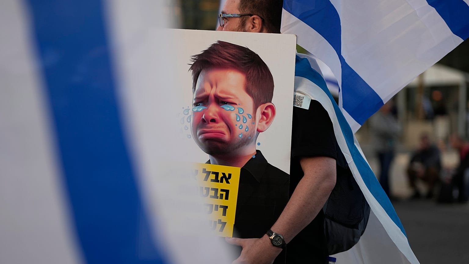 Egy kormányellenes tüntető a Netanjahu-fiú karikatúrájával