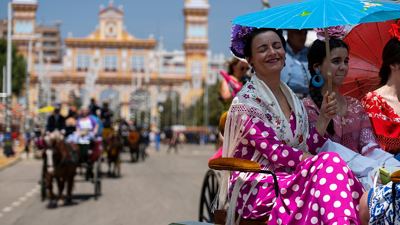 Mujeres en un coche de caballos resguardadas bajo una sombrilla en la tradicional Feria de Abril que se celebra todos los años en Sevilla, España, el 27 de abril de 2023.