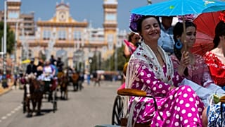 Mujeres en un coche de caballos resguardadas bajo una sombrilla en la tradicional Feria de Abril que se celebra todos los años en Sevilla, España, el 27 de abril de 2023.