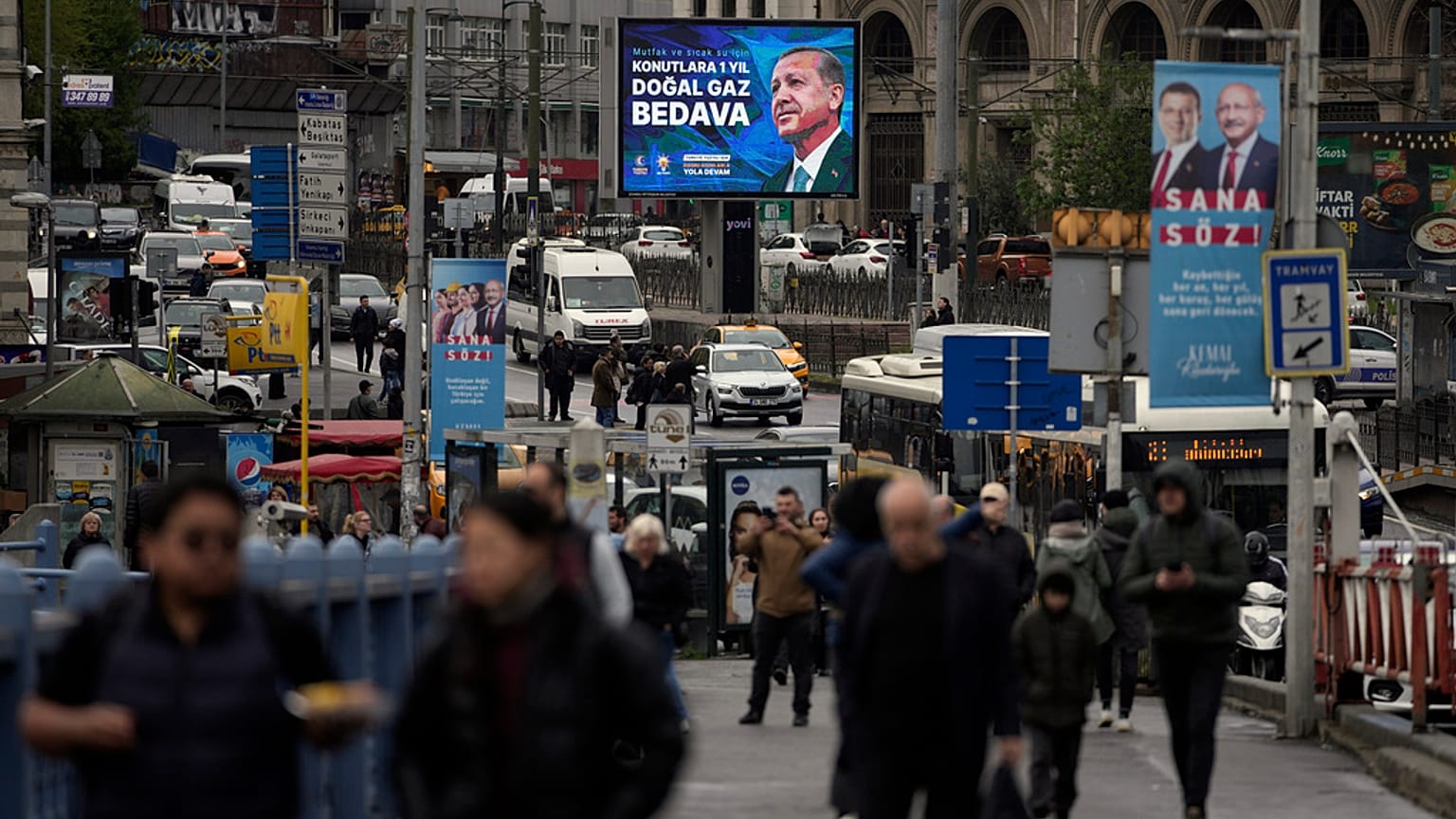 People walk by a billboard showing Turkish President and People's Alliance's presidential candidate Recep Tayyip Erdogan, in Istanbul, Turkey, Thursday, April 27, 2023. 