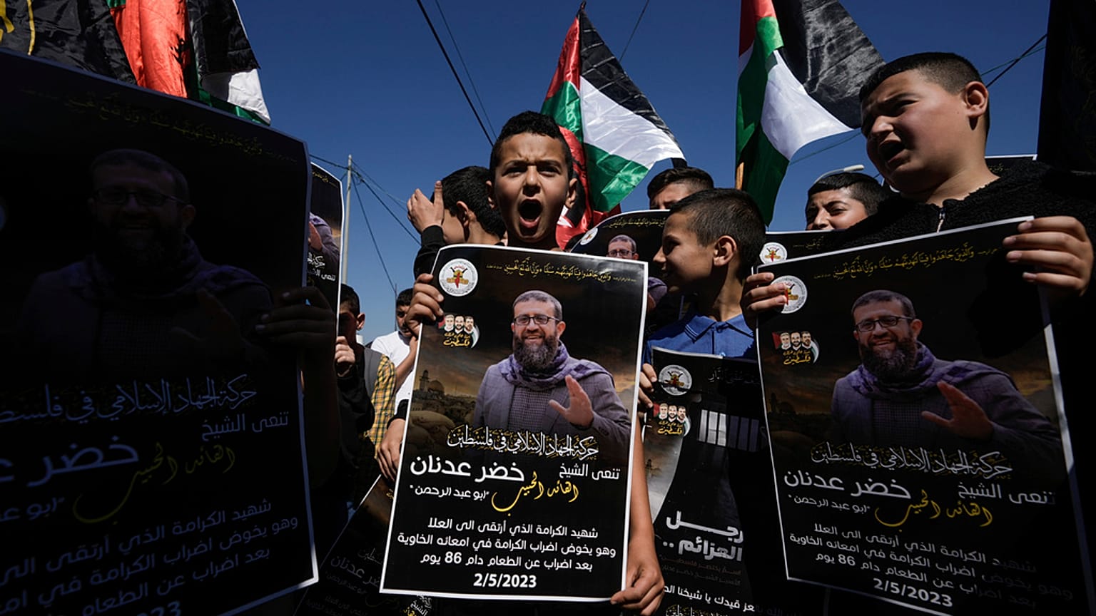 Palestinian kids wave their national flag and hold posters showing Khader Adnan, a Palestinian Islamic Jihad militant who died in Israeli prison. May 2, 2023
