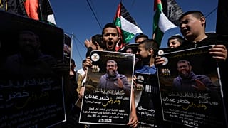 Palestinian kids wave their national flag and hold posters showing Khader Adnan, a Palestinian Islamic Jihad militant who died in Israeli prison. May 2, 2023