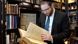 Rabbi Nicky Liss looks through items in a collection of memorabilia related to the history of British Jews, in London, Friday, April 28, 2023