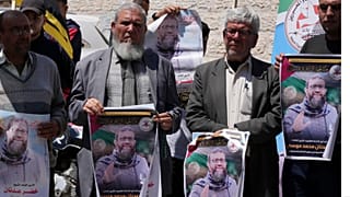 فلسطينيون يحملون صور الأسير خضر عدنان الذي توفي في سجن إسرائيلي، خلال اعتصام أمام مكتب اللجنة الدولية للصليب الأحمر، غزة، 2 مايو 2023.