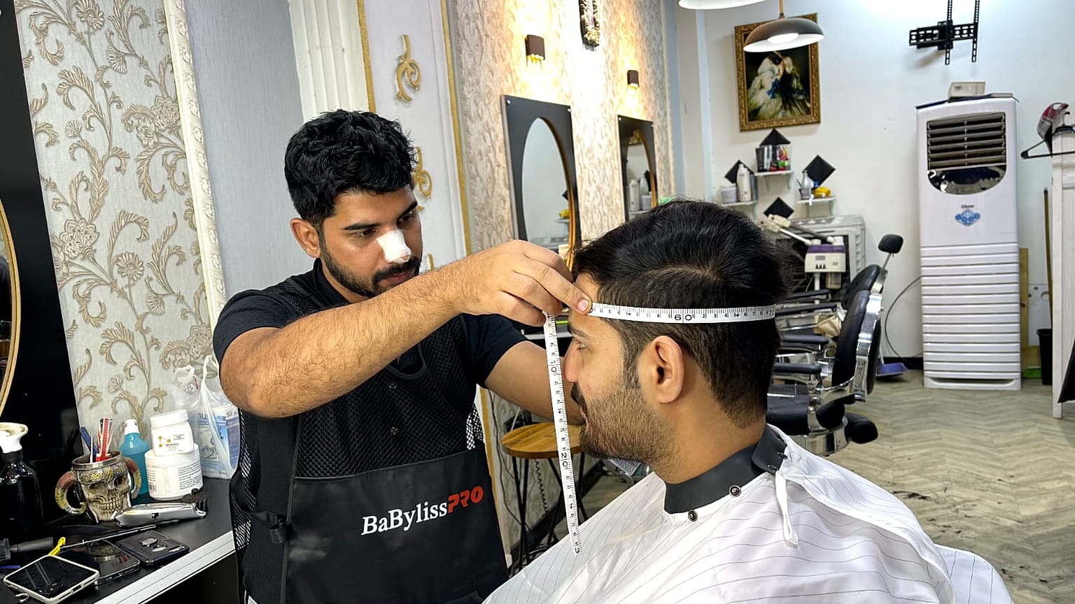 الحلاق العراقي مصطفى الشيرازي يقوم بأخذ قياسات رأس أحد الزبائن
